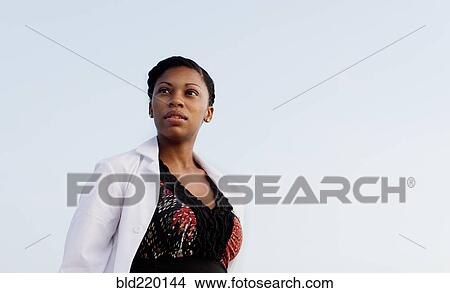 Picture - Serious doctor standing under blue sky. Fotosearch