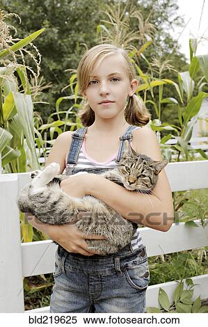 Stock Photography - Serious girl holding cat in garden. Fotosearch
