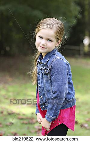 Stock Image - Serious girl standing in rural field. Fotosearch