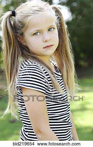 Picture - Serious girl with pigtails standing in field. Fotosearch