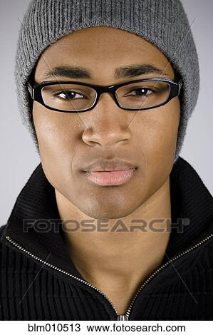 Stock Image - Serious mixed race man in eyeglasses and cap. Fotosearch