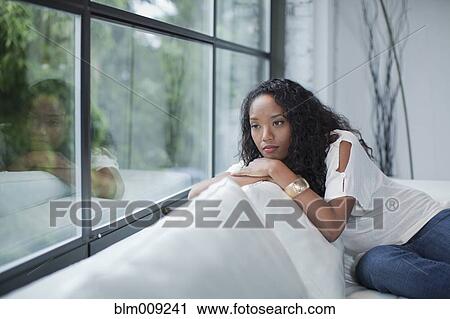 Stock Image - Serious mixed race woman looking out window. Fotosearch