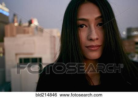 Stock Photograph - Serious mixed race woman on urban rooftop. Fotosearch