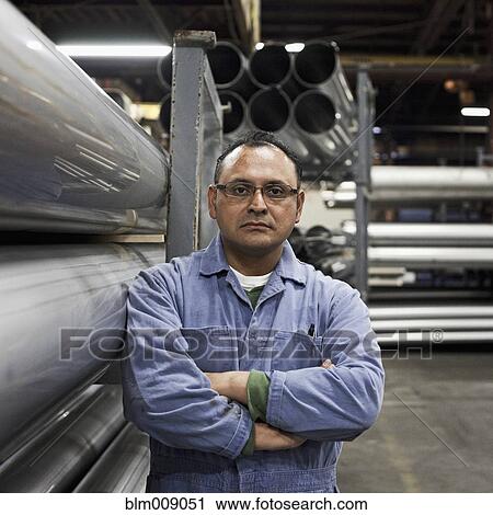 Serious mixed race worker standing near metal pipes in factory View Large Photo Image Stock Image - Serious mixed race worker standing near metal pipes in factory. Fotosearch