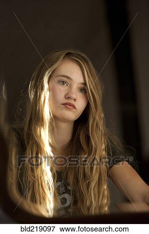 Stock Photo - Serious teenage girl examining herself in mirror. Fotosearch