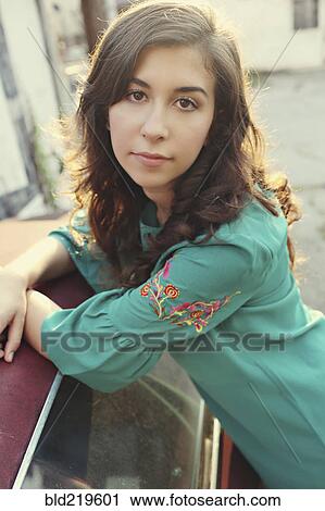 Stock Image - Serious teenage girl leaning on car. Fotosearch