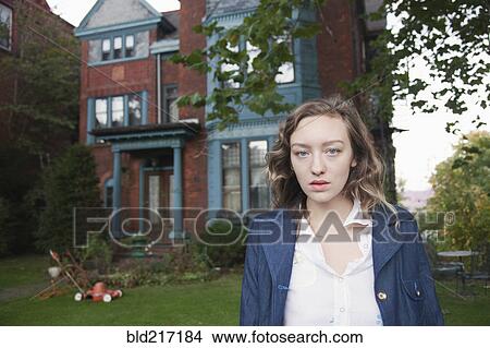 Serious woman standing in front yard View Large Photo Image Picture - Serious woman standing in front yard. Fotosearch