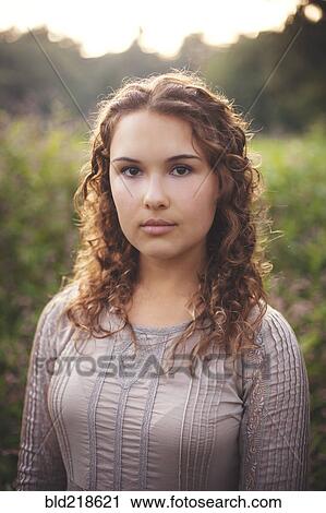 Stock Image - Serious woman standing in rural field. Fotosearch
