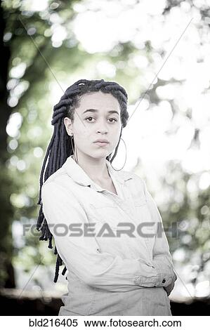 Stock Photography - Serious woman with dreadlocks standing outdoors. Fotosearch