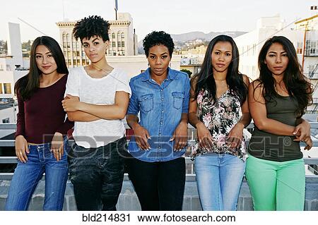 Stock Image - Serious women standing on urban rooftop. Fotosearch