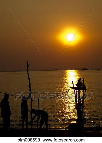 Silhouettes of men standing near river at sunset View Large Photo Image Stock Photo - Silhouettes of men standing near river at sunset. Fotosearch