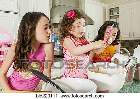 Stock Image - Sisters baking in kitchen. Fotosearch