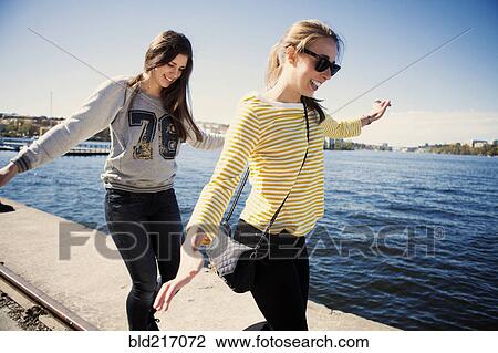 Stock Image - Sisters exploring waterfront. Fotosearch
