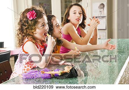 Stock Photo - Sisters sitting at counter. Fotosearch