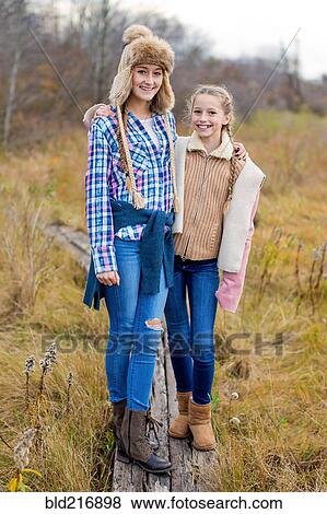 Sisters smiling on wooden walkway in field View Large Photo Image Stock Photo - Sisters smiling on wooden walkway in field. Fotosearch
