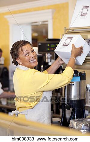 Stock Image - Small business owner lifting boxes in bakery. Fotosearch