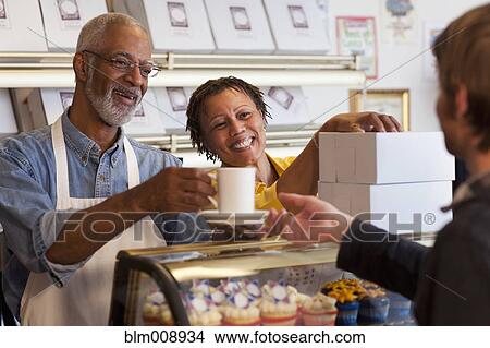Picture - Small business owners working in bakery together. Fotosearch