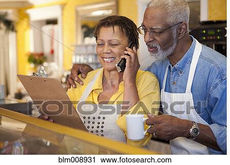 Stock Image - Small business owners working in bakery together. Fotosearch