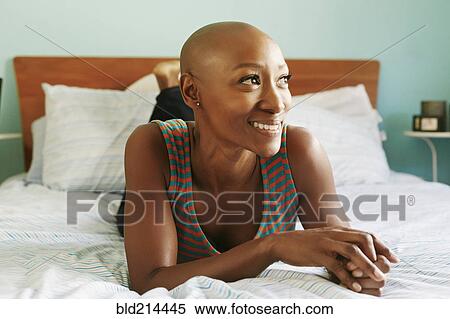 Stock Photography - Smiling African American woman laying on bed. Fotosearch