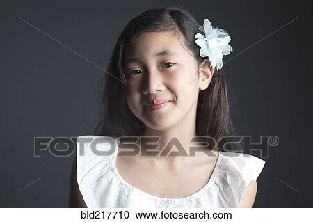 Stock Image - Smiling Asian girl wearing flower in her hair. Fotosearch