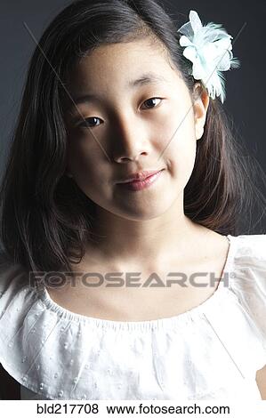 Smiling Asian girl wearing flower in her hair View Large Photo Image Stock Photo - Smiling Asian girl wearing flower in her hair. Fotosearch