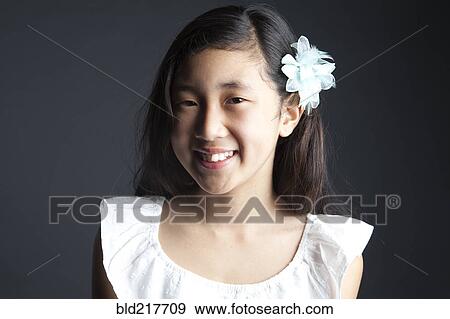 Stock Photo - Smiling Asian girl wearing flower in her hair. Fotosearch