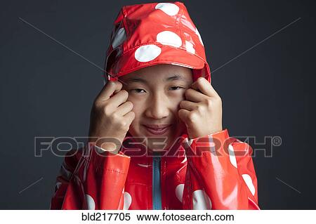 Stock Photography - Smiling Asian girl wearing hooded raincoat. Fotosearch