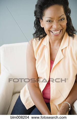 Smiling Black woman sitting on armchair View Large Photo Image Picture - Smiling Black woman sitting on armchair. Fotosearch