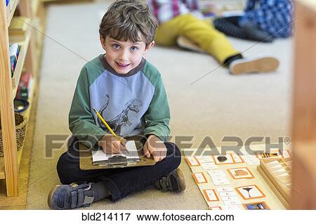 Smiling boy writing in classroom View Large Photo Image Stock Photo - Smiling boy writing in classroom. Fotosearch