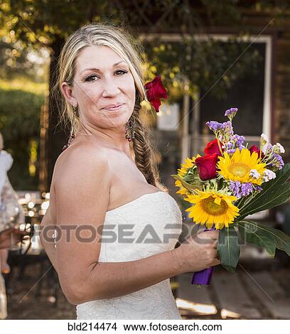 Smiling Caucasian bride holding bouquet of flowers View Large Photo Image Picture - Smiling Caucasian bride holding bouquet of flowers. Fotosearch