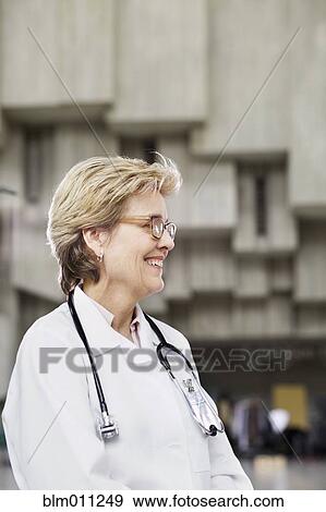 Stock Photo - Smiling Caucasian doctor standing outdoors. Fotosearch
