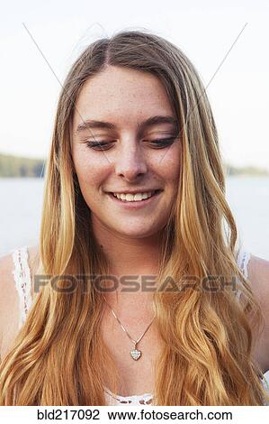 Stock Image - Smiling Caucasian teenage girl looking down. Fotosearch