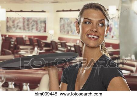 Stock Photography - Smiling Caucasian waitress carrying tray. Fotosearch