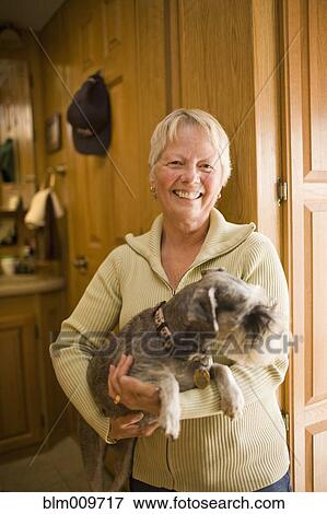 Stock Photo - Smiling Caucasian woman holding dog. Fotosearch