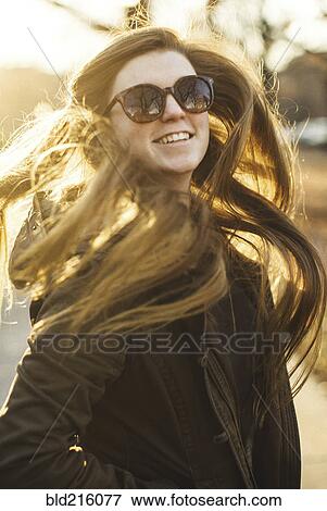 Stock Photo - Smiling Caucasian woman tossing her hair outdoors. Fotosearch