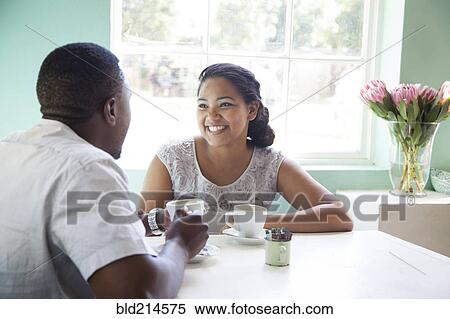 Stock Photography - Smiling couple drinking coffee at table. Fotosearch