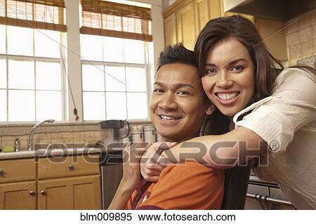Stock Photography - Smiling couple hugging in kitchen. Fotosearch