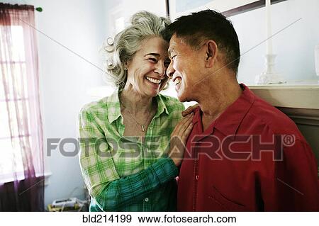 Stock Photo - Smiling couple hugging in living room. Fotosearch