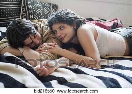 Stock Image - Smiling couple laying on bed. Fotosearch