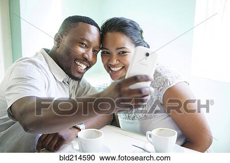 Smiling couple taking cell phone selfie View Large Photo Image Stock Image - Smiling couple taking cell phone selfie. Fotosearch