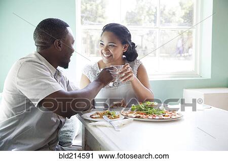 Stock Image - Smiling couple toasting at table. Fotosearch