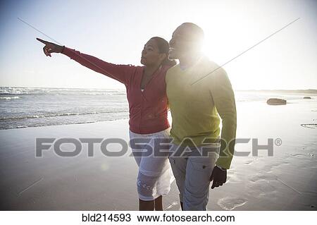 Stock Image - Smiling couple walking on beach. Fotosearch