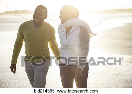Stock Photography - Smiling couple walking on beach. Fotosearch