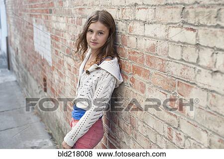 Stock Photo - Smiling girl leaning on brick wall. Fotosearch