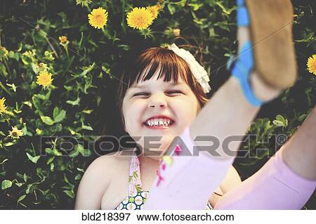 Smiling girl playing in grass with flowers, View Large Photo Image Stock Photo - Smiling girl playing in grass with flowers,. Fotosearch