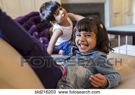 Smiling girl playing on sofa in living room View Large Photo Image Stock Image - Smiling girl playing on sofa in living room. Fotosearch