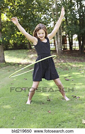Smiling girl playing with plastic hoop in field View Large Photo Image Stock Image - Smiling girl playing with plastic hoop in field. Fotosearch