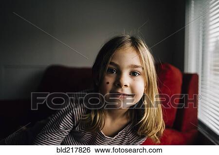 Stock Photograph - Smiling girl sitting in armchair. Fotosearch