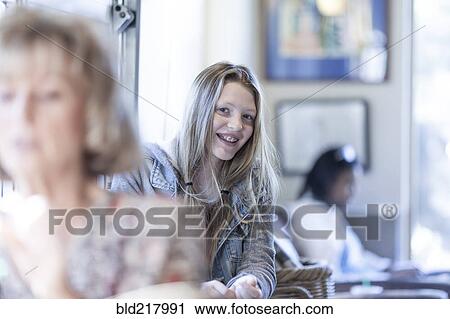 Stock Image - Smiling girl sitting in waiting area. Fotosearch