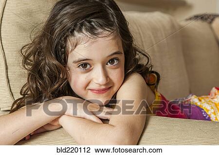 Smiling girl sitting on sofa View Large Photo Image Stock Image - Smiling girl sitting on sofa. Fotosearch
